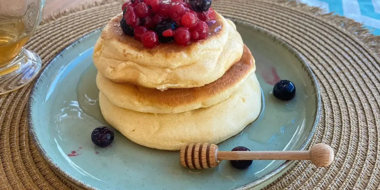Pancake con albumi soffici, guarniti con frutti di bosco e miele. Un dolce leggero e goloso.