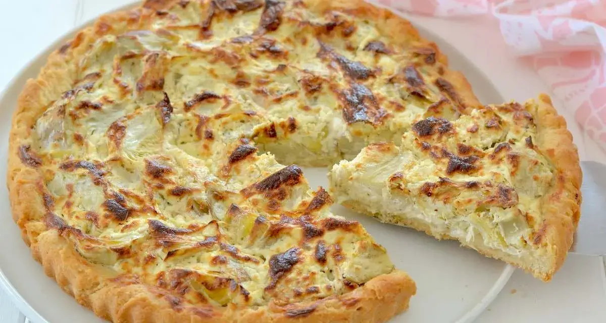 Una deliziosa torta salata con carciofi, dorata e invitante, con una fetta appena tagliata che mostra il ripieno cremoso.