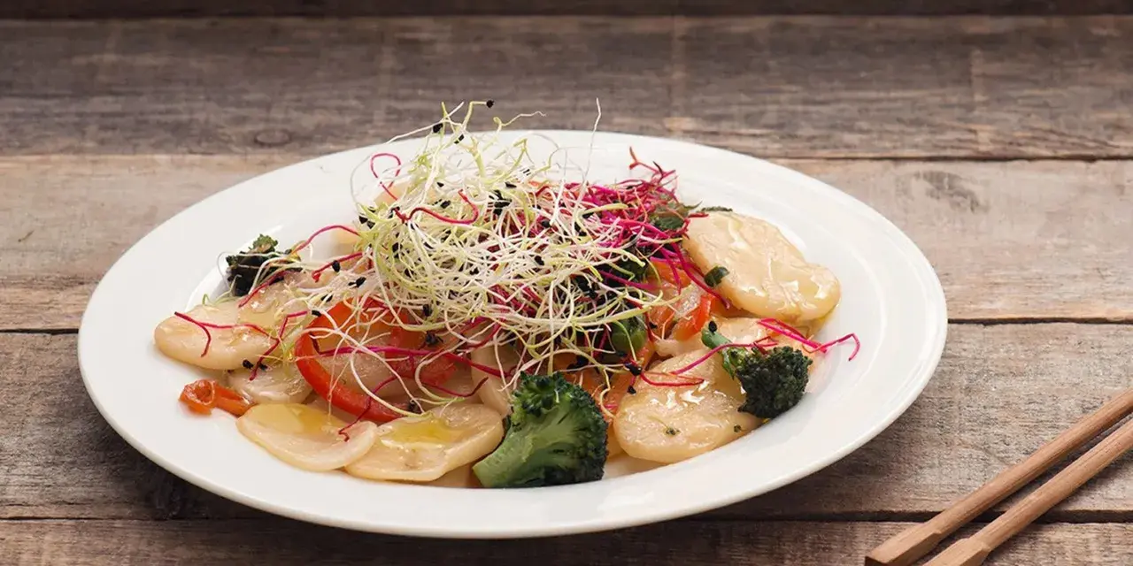 Gnocchi di riso con verdure croccanti e germogli freschi, un piatto leggero e colorato.