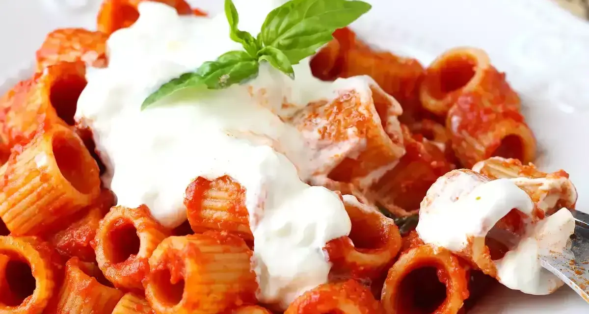 Rigatoni al sugo rosso con abbondante stracciatella cremosa e una fogliolina di basilico.