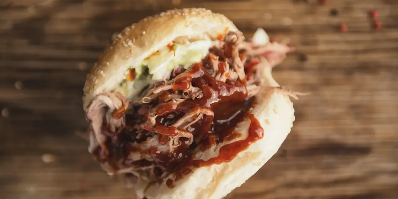 Un panino succulento con pulled pork, salsa barbecue e insalata di cavolo, perfetto per chi cerca una ricetta facile e gustosa.