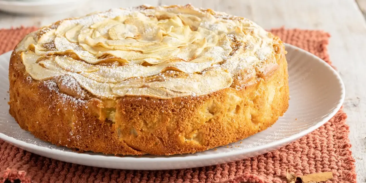 Deliziosa torta di mele senza burro, con mele a rosa sulla superficie e una spolverata di zucchero a velo. Perfetta per una colazione leggera.