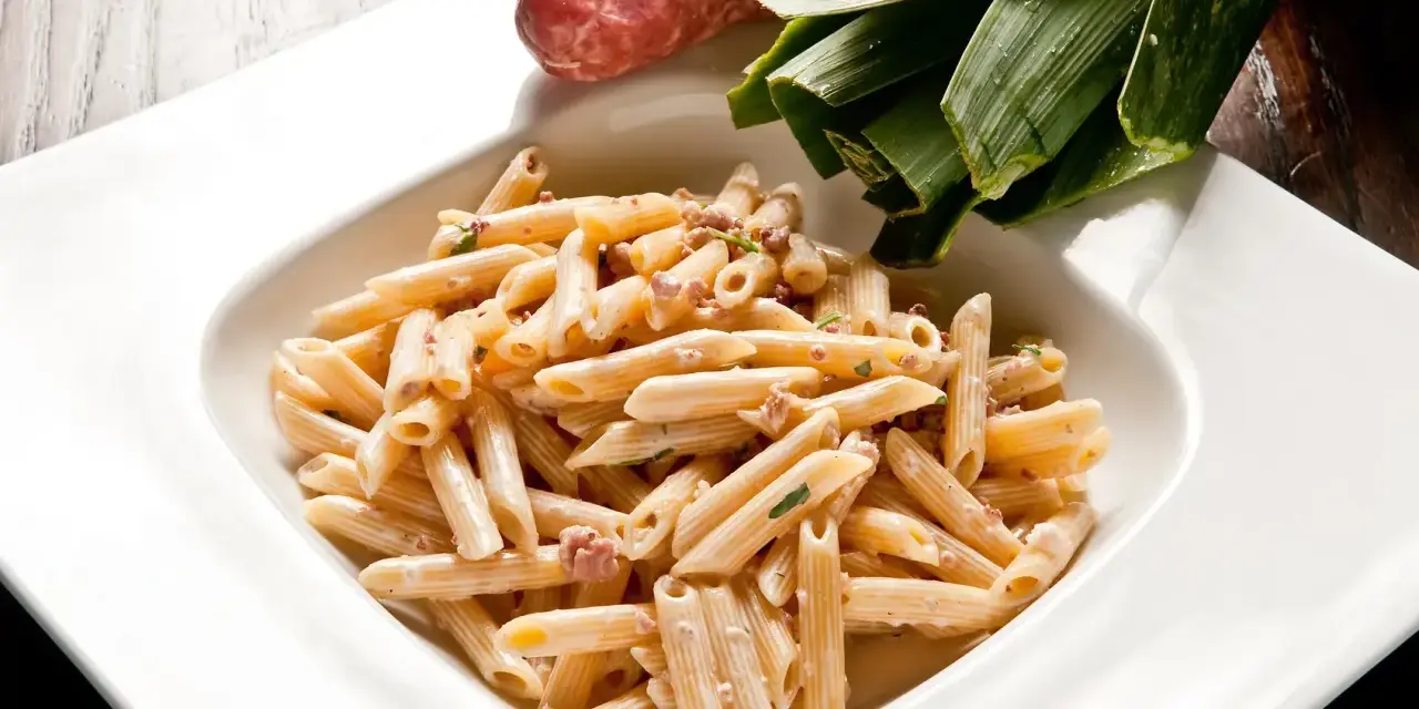 Penne cremose con salsiccia e verdure, un piatto di pasta alla norcina pronto per essere gustato.