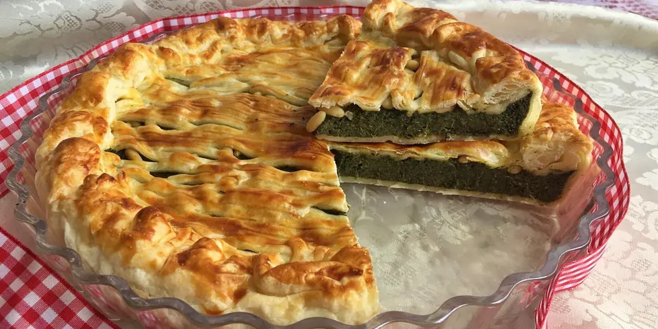 Torta salata ricotta e spinaci dorata e invitante, con una fetta tagliata che mostra il ripieno verde e cremoso.