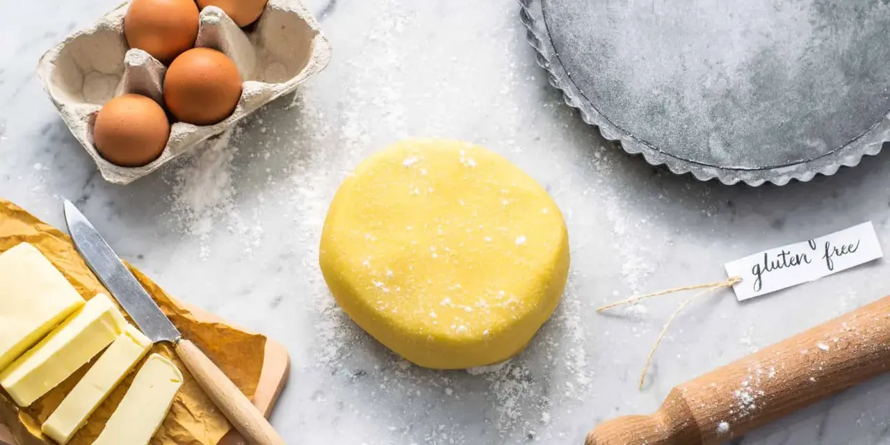 Impasto giallo brillante per una deliziosa pasta frolla senza glutine, pronto con uova, burro e una teglia.