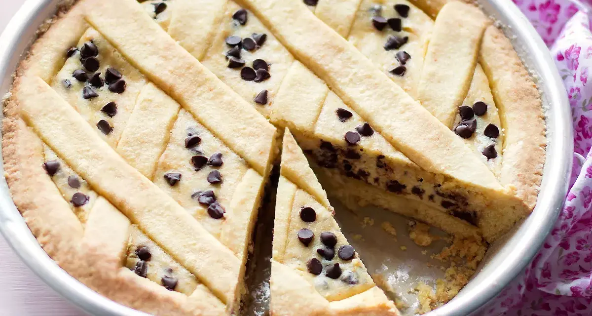 Deliziosa crostata ricotta e cioccolato con un reticolo di pasta frolla e gocce di cioccolato fondente.