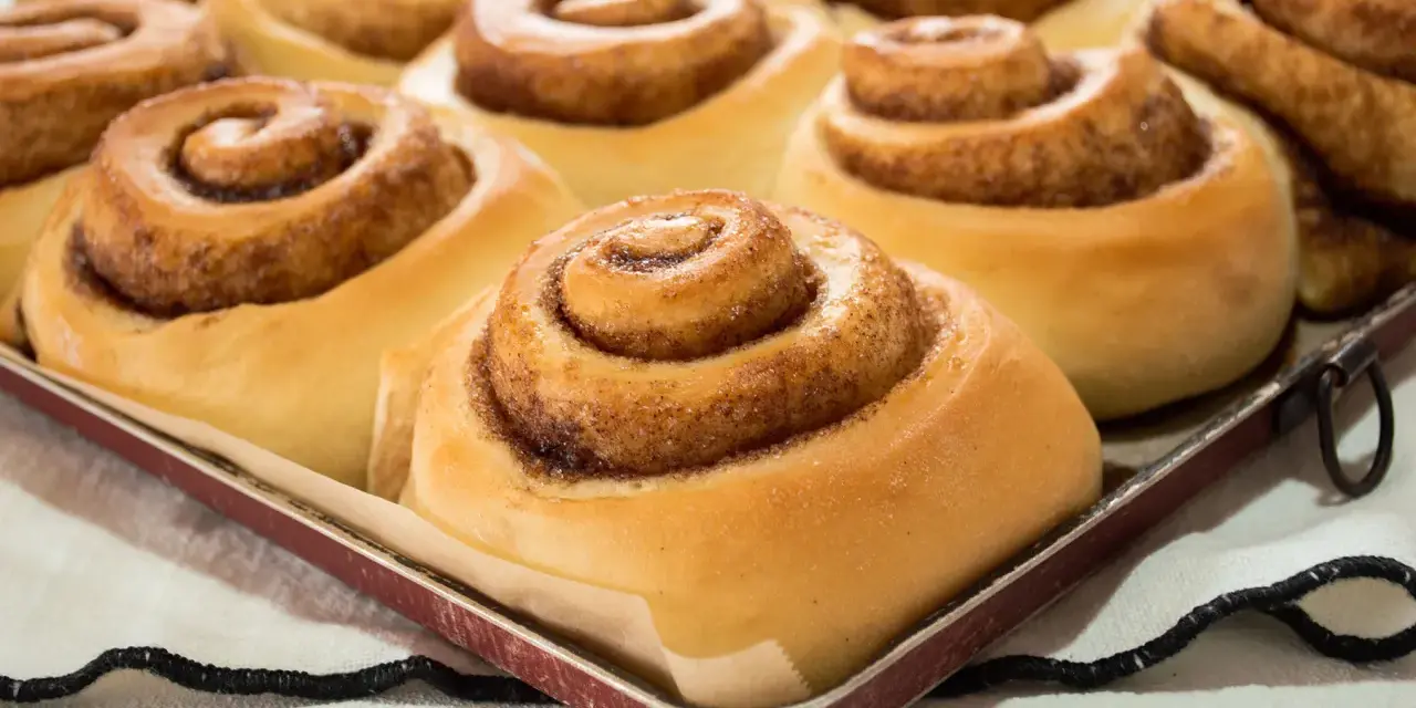 Dolci cinnamon rolls appena sfornati, pronti per essere gustati. Una ricetta perfetta per la colazione o la merenda.