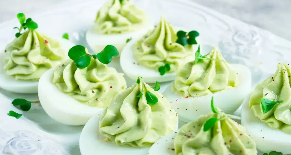 Uova ripiene per Pasqua, guarnite con crema verde e germogli freschi, un antipasto colorato e delizioso.