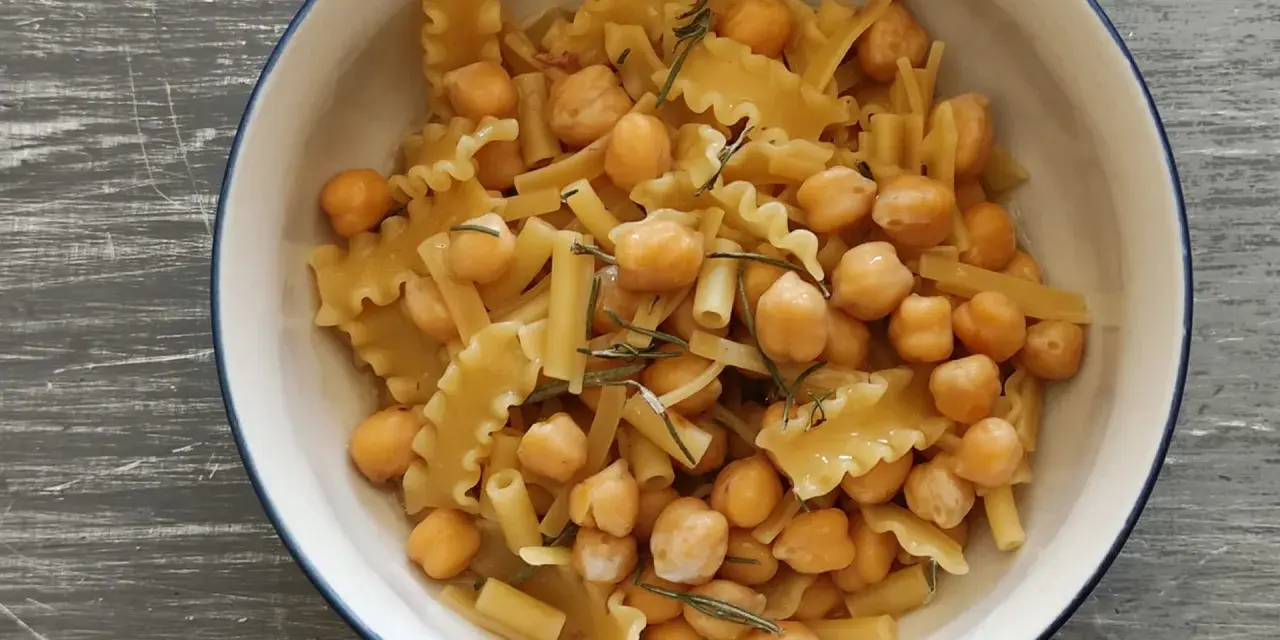 Un piatto invitante di pasta e ceci, con pasta corta e ceci dorati, guarnito con rosmarino fresco.