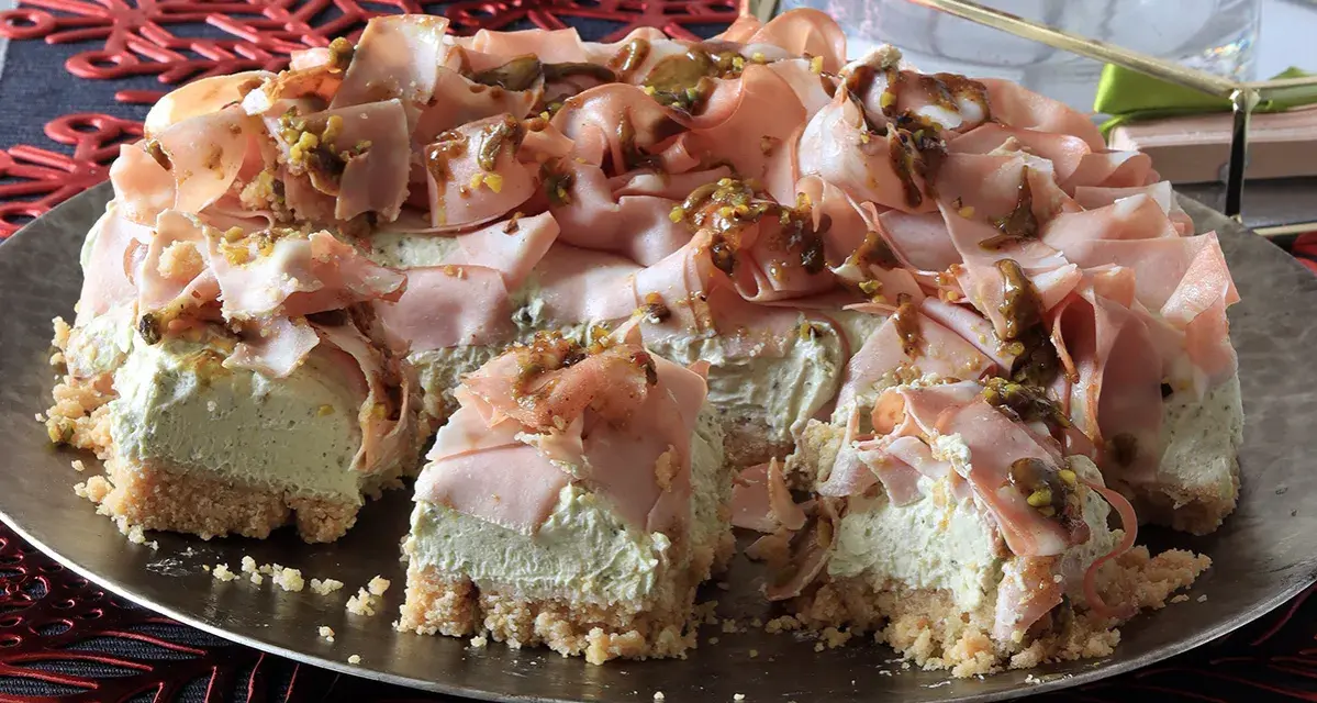 Cheesecake salata con taralli, mortadella e pistacchi. Una torta scenografica e gustosa, perfetta per un aperitivo o un antipasto originale.