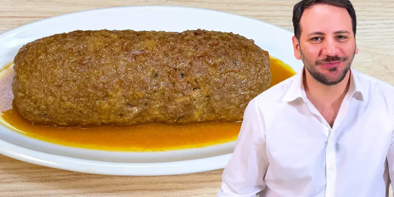 Un uomo sorride accanto a un succulento polpettone in padella, pronto per essere gustato.