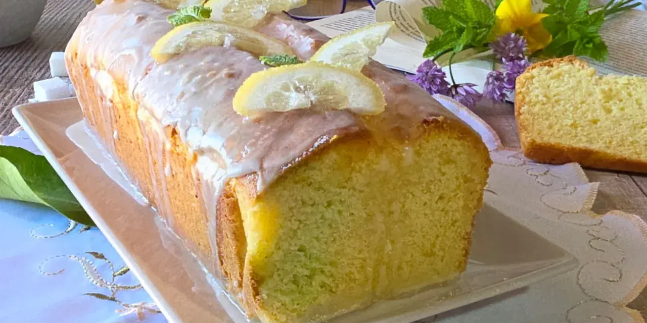 Un soffice plumcake al limone glassato, decorato con fette di limone e menta. Perfetto per una pausa golosa.