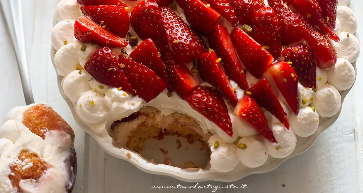 Delizioso tiramisù alle fragole, con panna montata, fragole fresche e pistacchi. Una fetta è già servita su un cucchiaio.
