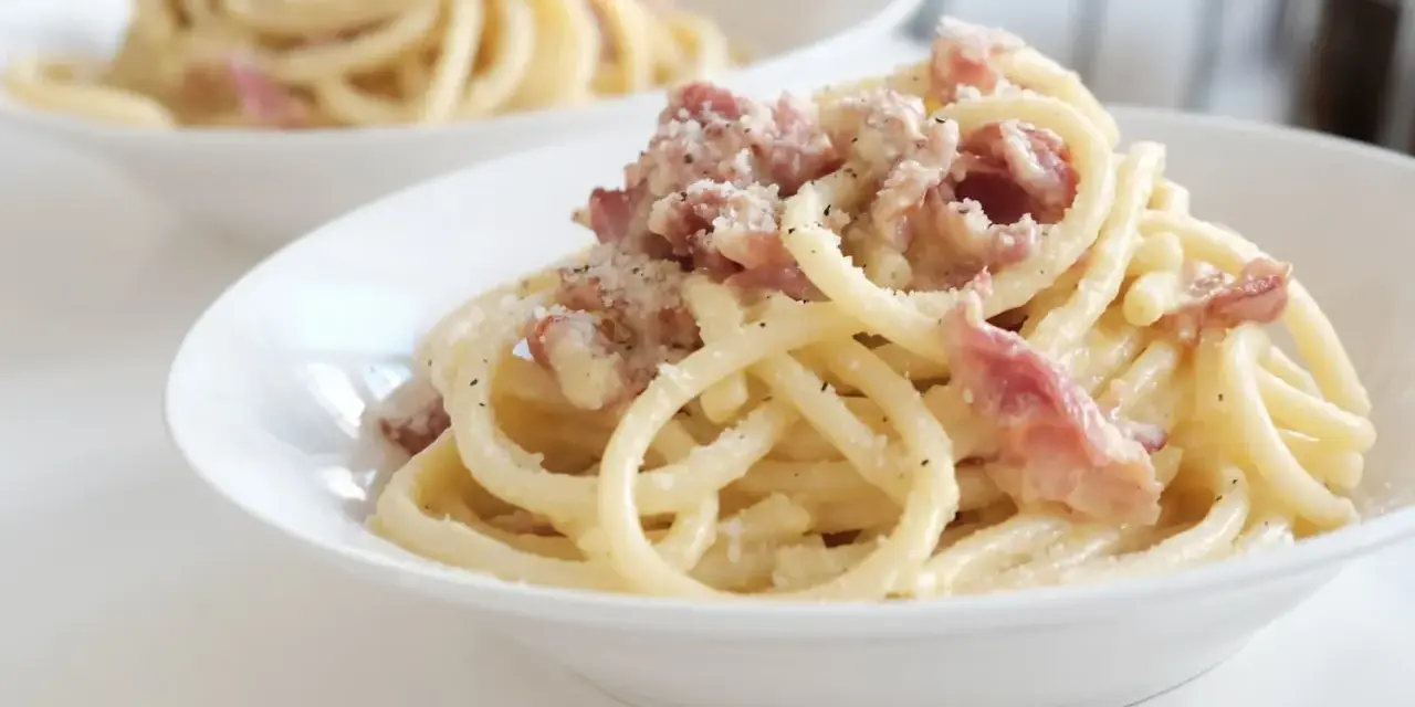 Un piatto di pasta alla gricia fumante, con guanciale croccante e pecorino romano grattugiato.