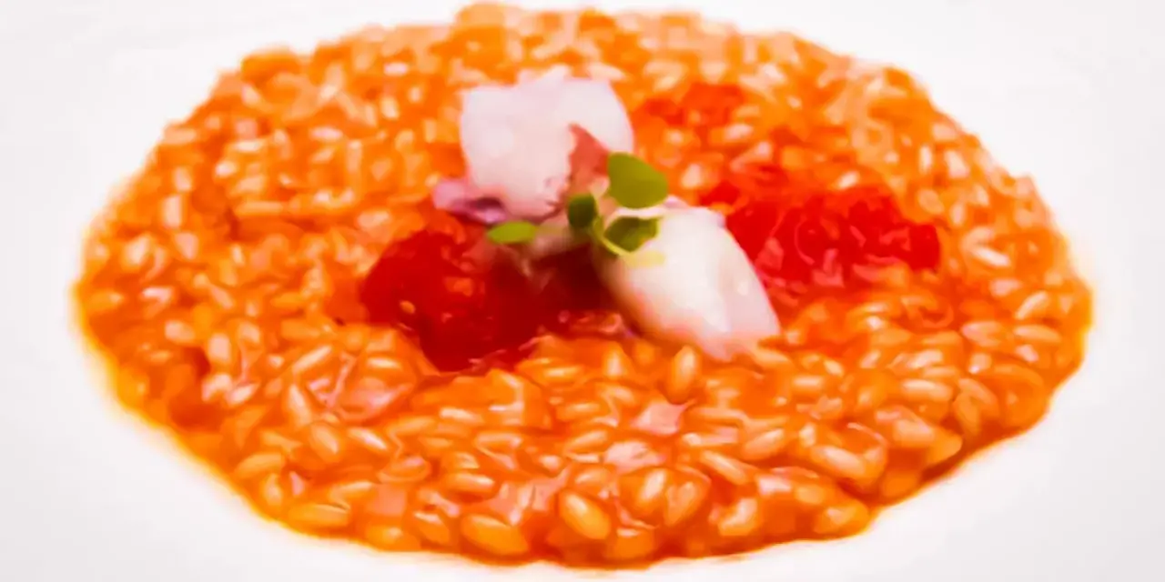 Un cremoso risotto al pomodoro, guarnito con calamari teneri, pomodorini e germogli freschi. Un piatto che celebra i sapori dell'Italia.