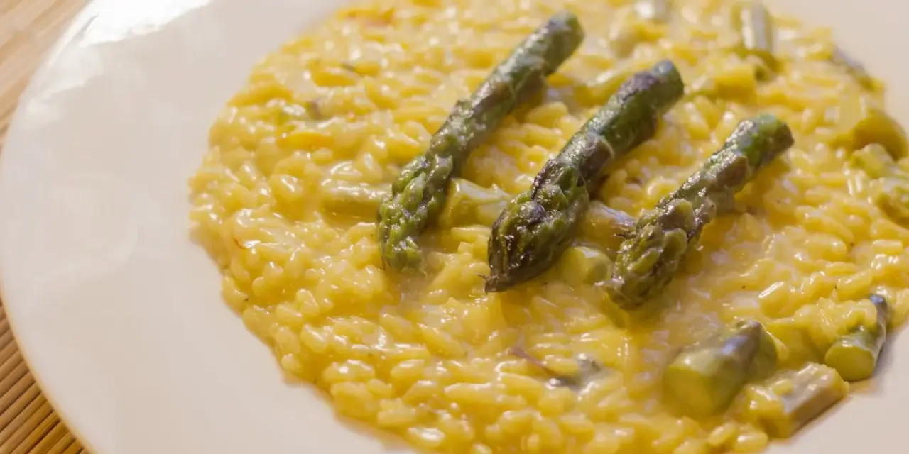 Risotto cremoso con asparagi e zafferano, un piatto primaverile che profuma di sole.