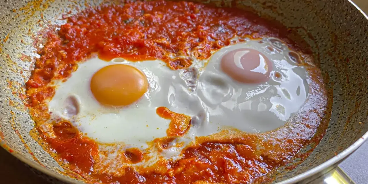 Uova in purgatorio, due uova cotte in una salsa rossa piccante, in una padella.
