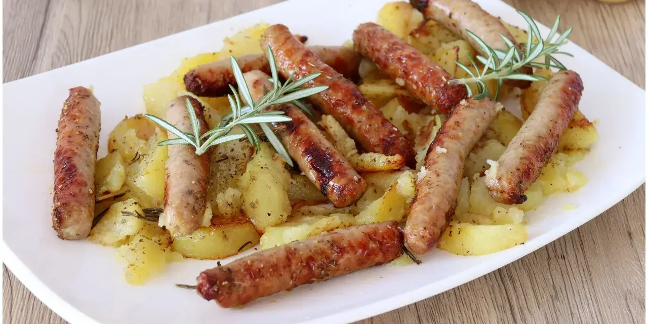 Salsiccia e patate al forno, un piatto rustico e saporito, con rosmarino fresco che profuma il tutto.