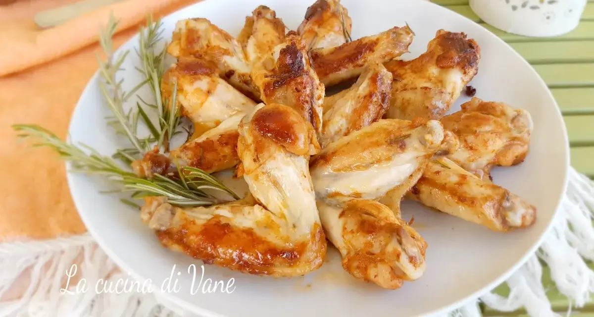 A plate of golden-brown, juicy chicken wings garnished with rosemary sprigs.