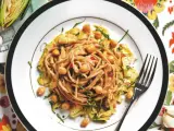 Un piatto invitante di pasta con carciofi alla siciliana, arricchito da ceci e erbe fresche, su un tovagliolo fiorito.
