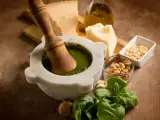 Mortaiolo in marmo con pestello in legno, basilico fresco, pinoli, noci, aglio, parmigiano e olio d'oliva, ingredienti per un autentico pesto di basilico.