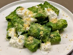 Paccheri conditi con un vibrante pesto di cavolo nero, arricchiti da ricotta fresca e pangrattato croccante.