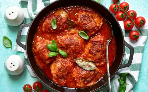 Pollo in umido succulento in padella con pomodoro e basilico, pronto per essere gustato.