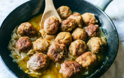 Polpette dorate in padella con cipolle, pronte per essere gustate. Un classico della cucina italiana.
