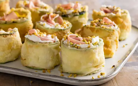 Rotolini di zucchine fritte con crema, prosciutto e pistacchi: stuzzichini veloci ed economici per aperitivo, perfetti per stupire gli ospiti.