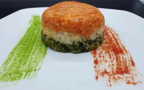 Un colorato timballo di riso a tre strati, con salse verdi e rosse che ricordano i colori di una bandiera.
