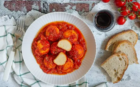 Polpette di ricotta al sugo, morbide e saporite, servite con pane casereccio e pomodorini freschi.