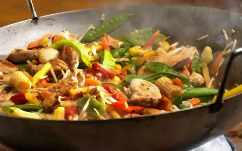 Straccetti di pollo saltati in padella con verdure colorate: piselli, carote, peperoni e germogli.