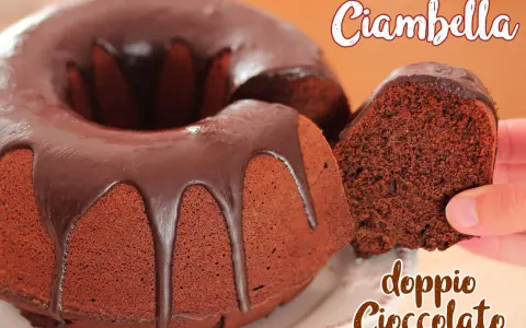 Ciambellone al cioccolato con glassa fondente. Una fetta viene sollevata, mostrando la consistenza soffice e il ricco colore del dolce.