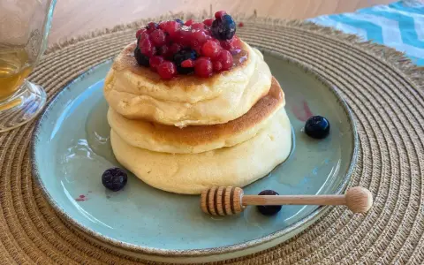 Pancake con albumi soffici, guarniti con frutti di bosco e miele. Un dolce leggero e goloso.