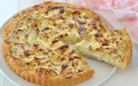 Una deliziosa torta salata con carciofi, dorata e invitante, con una fetta appena tagliata che mostra il ripieno cremoso.