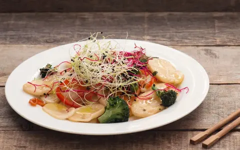 Gnocchi di riso con verdure croccanti e germogli freschi, un piatto leggero e colorato.