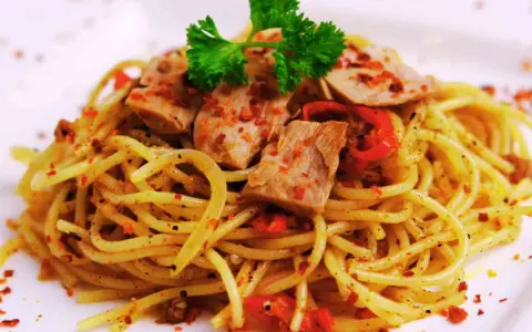Spaghetti conditi con tonno fresco, peperoncino e prezzemolo. Un piatto semplice e gustoso.