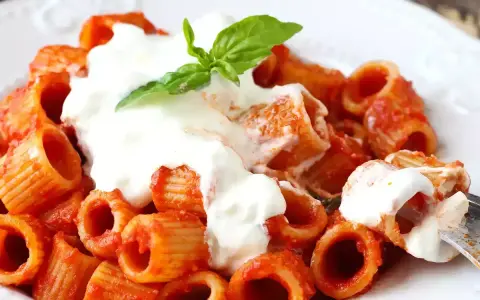 Rigatoni al sugo rosso con abbondante stracciatella cremosa e una fogliolina di basilico.