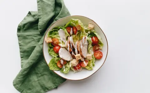 Deliziosa insalata di pollo con lattuga croccante, pomodorini succosi e crostini, condita con una cremosa salsa.