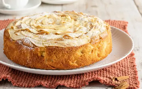 Deliziosa torta di mele senza burro, con mele a rosa sulla superficie e una spolverata di zucchero a velo. Perfetta per una colazione leggera.