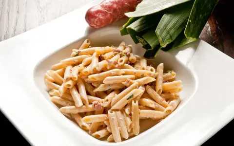 Penne cremose con salsiccia e verdure, un piatto di pasta alla norcina pronto per essere gustato.
