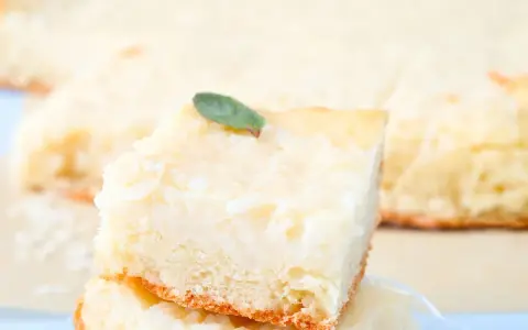 Una fetta di torta di riso carrarina, soffice e profumata, guarnita con una fogliolina verde.