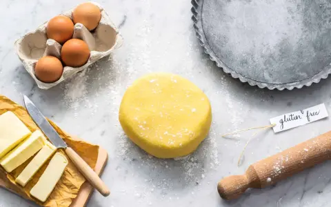 Impasto giallo brillante per una deliziosa pasta frolla senza glutine, pronto con uova, burro e una teglia.