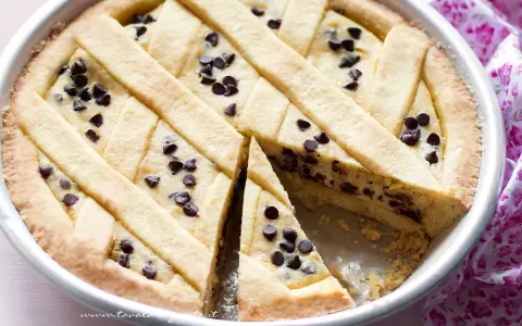 Deliziosa crostata ricotta e cioccolato con un reticolo di pasta frolla e gocce di cioccolato fondente.