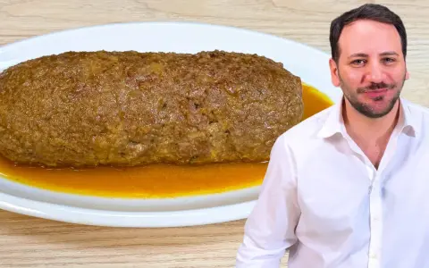 Un uomo sorride accanto a un succulento polpettone in padella, pronto per essere gustato.