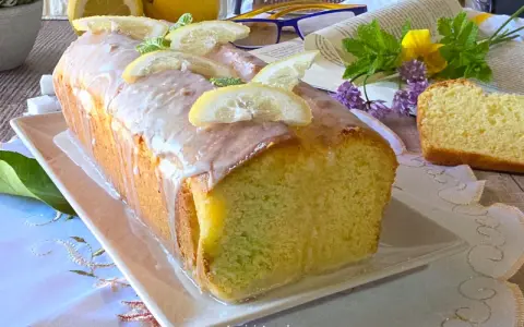 Un soffice plumcake al limone glassato, decorato con fette di limone e menta. Perfetto per una pausa golosa.