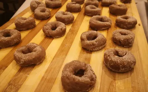 Ciambelline al vino pronte per essere gustate, cosparse di zucchero su un tagliere di legno.