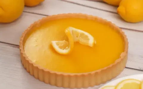 Una deliziosa crostata al limone, con la sua crema gialla brillante e decorata con spicchi di limone fresco.