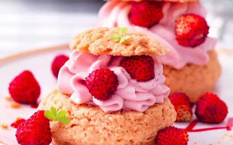 Deliziosa mousse di fragole su bignè, guarnita con fragoline di bosco e foglioline verdi.