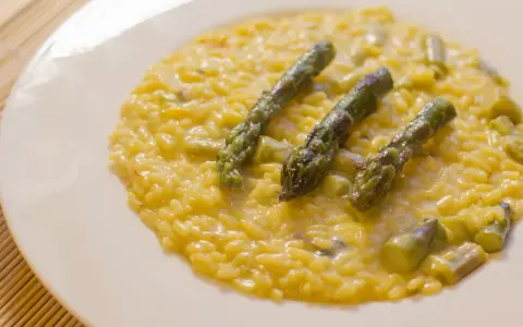 Risotto cremoso con asparagi e zafferano, un piatto primaverile che profuma di sole.